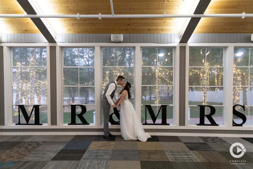 A couple kissing in front of windows with the letters r & m