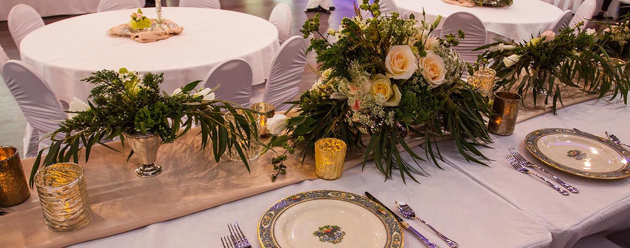 A table set with plates and silverware, flowers.