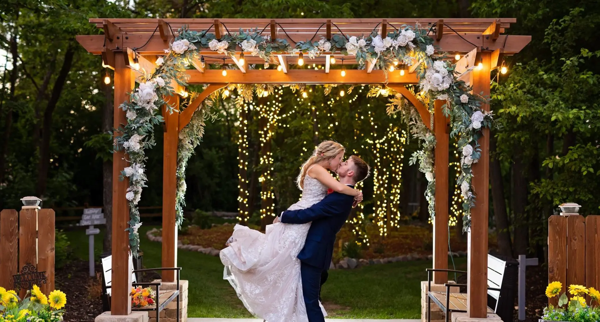 A bride and groom are dancing under the arbor.