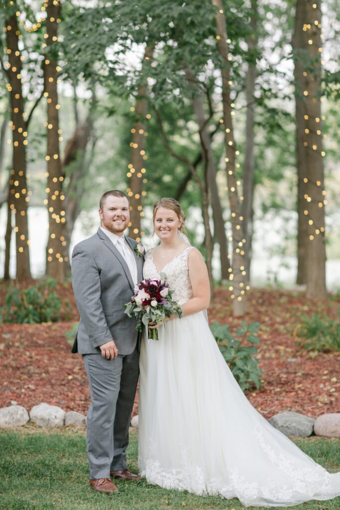 A bride and groom pose for a picture in the woods.