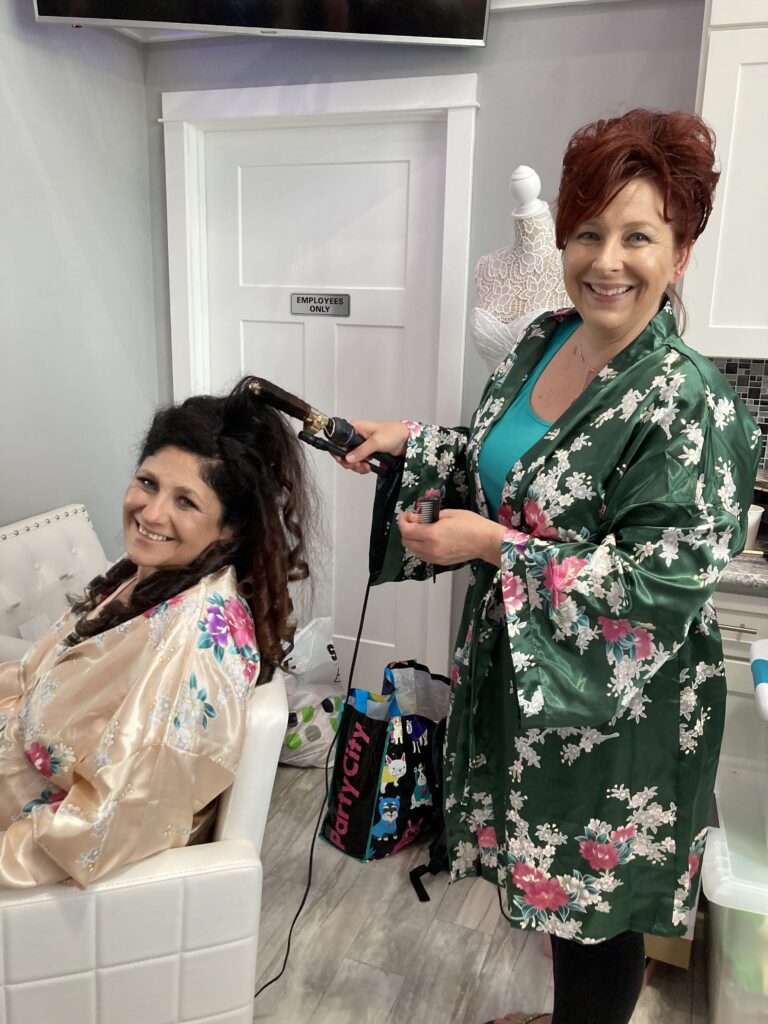 A woman in floral robe getting her hair done.