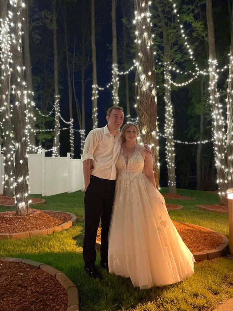 A man and woman posing for a picture in front of trees.