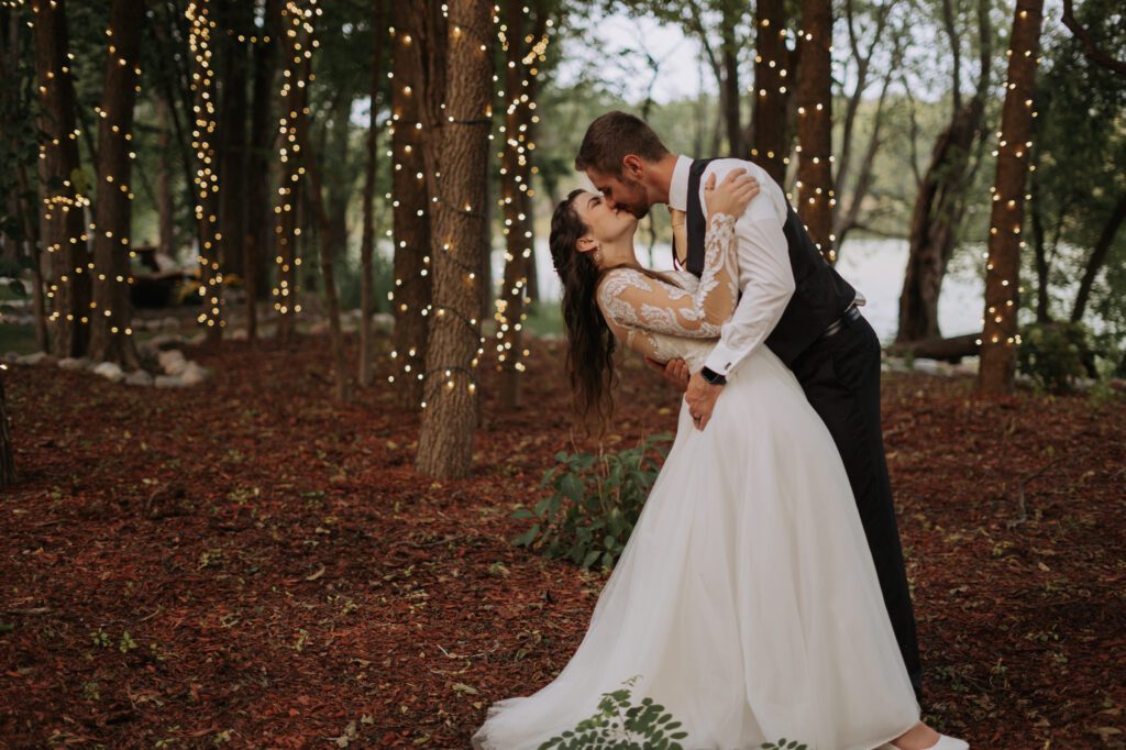 A bride and groom kissing in the woods