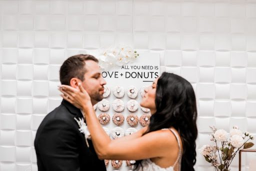 A man and woman kissing in front of donuts.