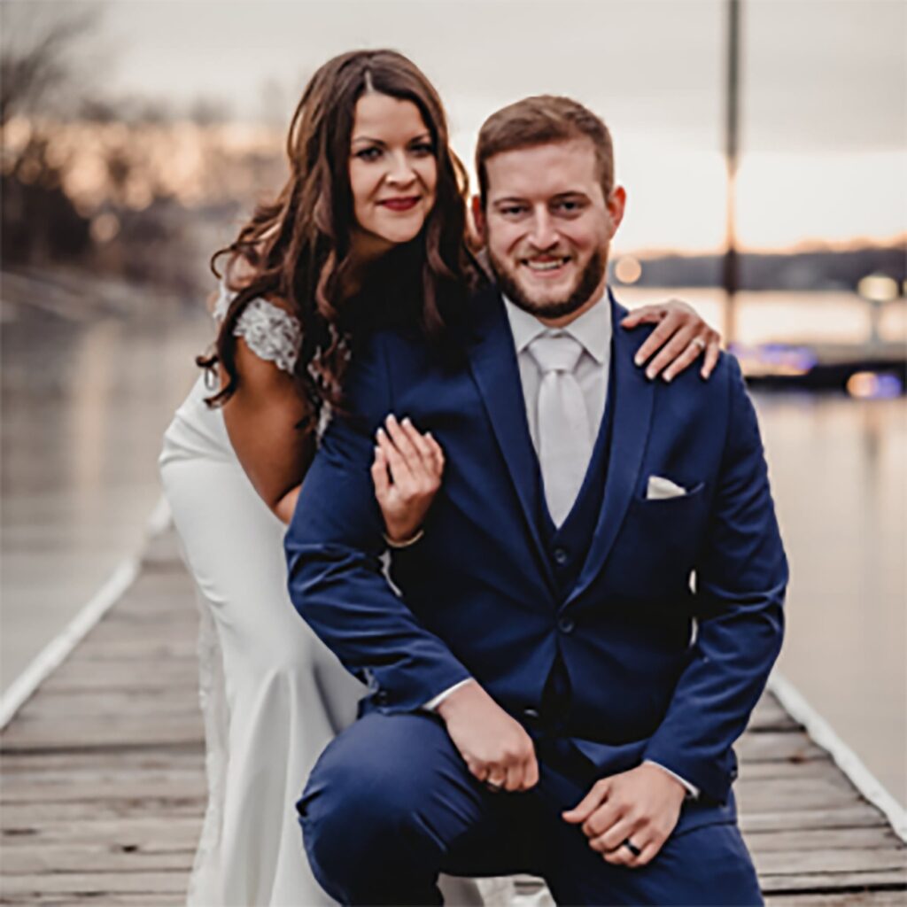 bride and groom taking photos in front of a dock