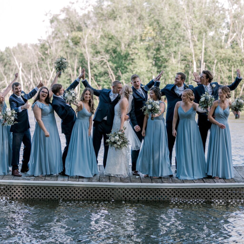 a bride and groom kissing next to their bridesmaids and groomsmen