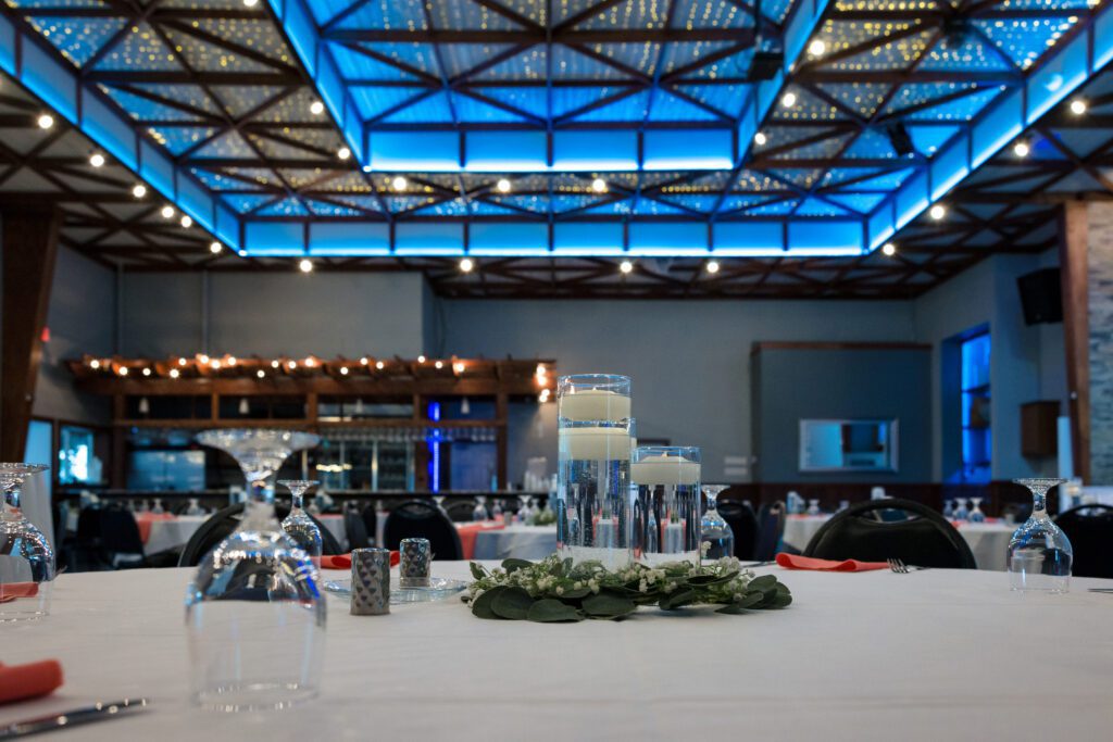 A banquet hall with blue lighting and white tables.