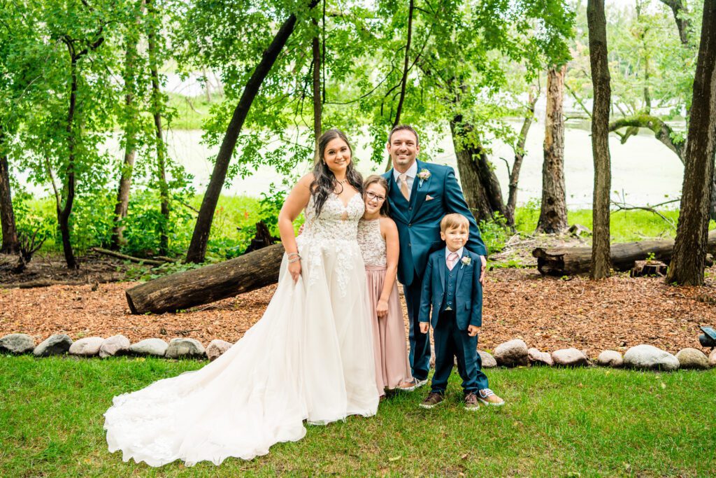 A bride and groom posing with their two children.