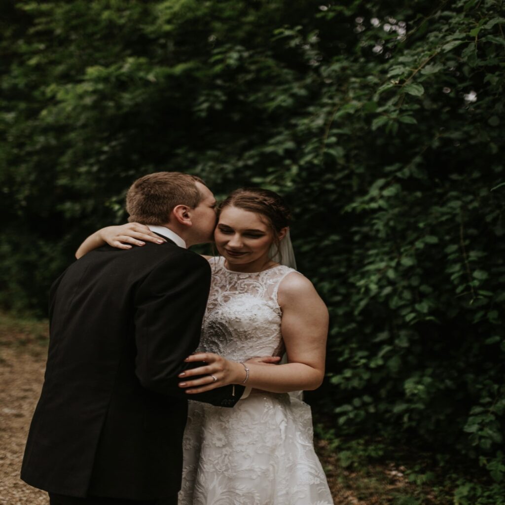 A bride and groom kissing in front of trees.
