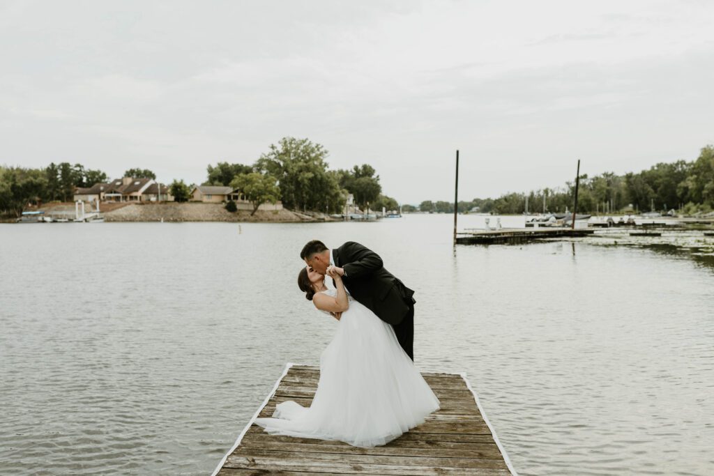 A bride and groom kissing on the dock