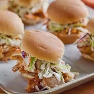 A tray of pulled pork sandwiches with cole slaw.