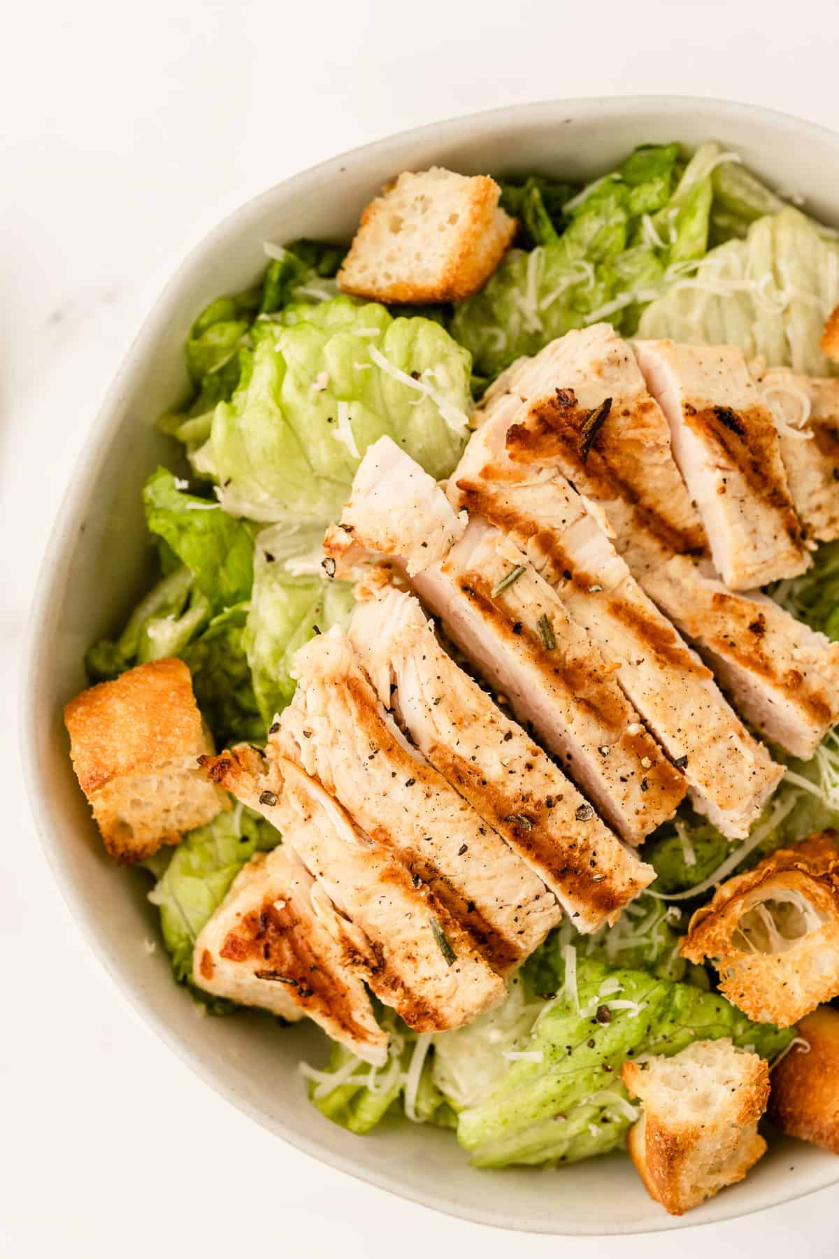 A salad with chicken and croutons in it.