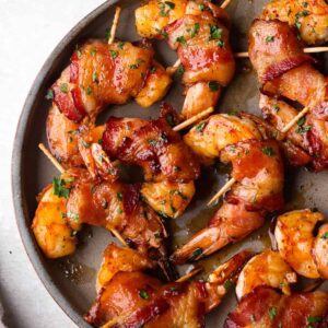 A pan of bacon wrapped shrimp on skewers.