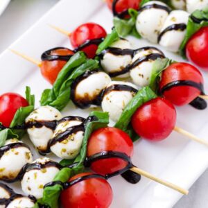 A white plate topped with skewers of food.