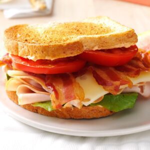 A sandwich with bacon, cheese and tomatoes on it.