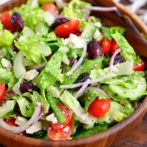 A wooden bowl filled with salad and tomatoes.