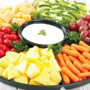 A platter of fruit and vegetables with dip.