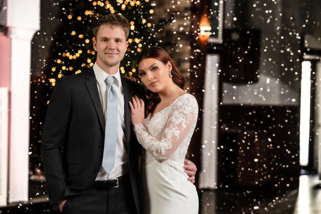 A man and woman posing for a picture in front of a christmas tree.