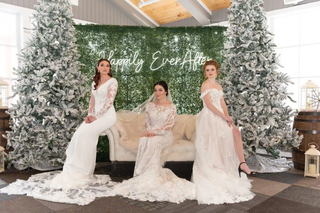 Three women in white gowns posing on a couch.