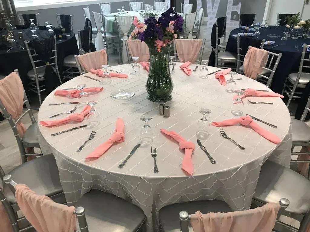 A round table with silverware and pink napkins.