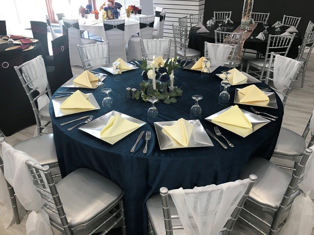 A table with many place settings and silver chairs