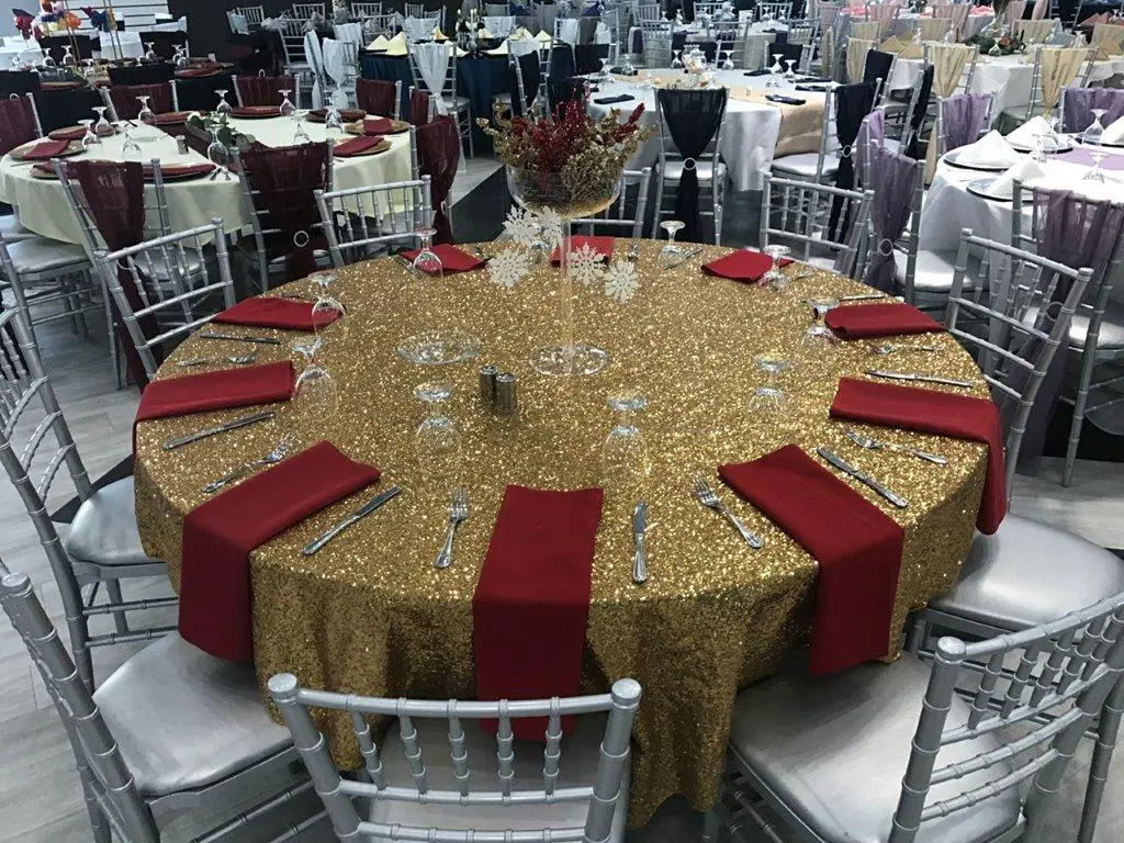 A table with red napkins and gold tablecloth