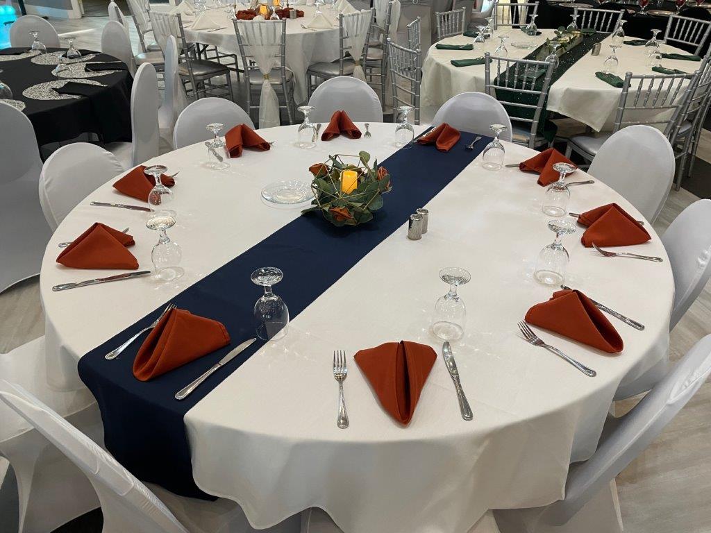 A table set up with white tables and red napkins.