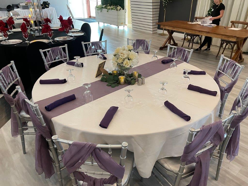 A table with purple napkins and white tablecloth
