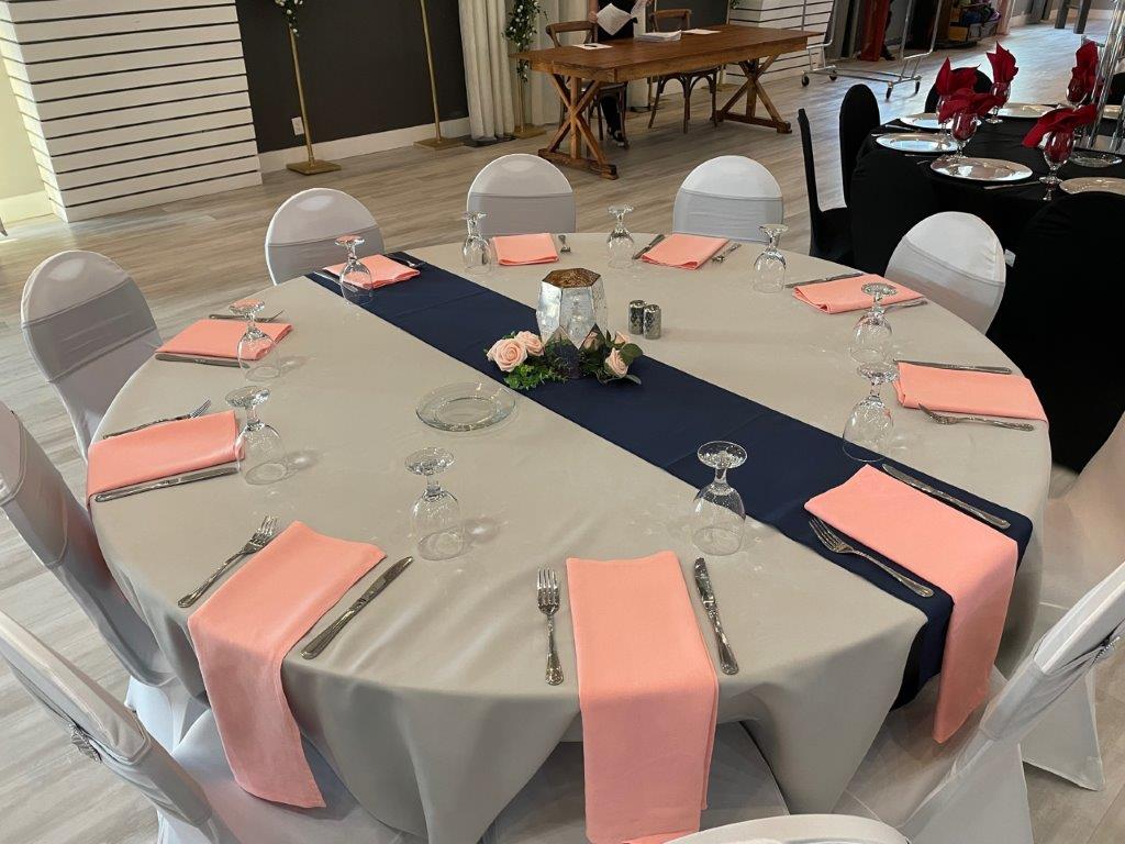 A table set up with pink napkins and grey tablecloth.