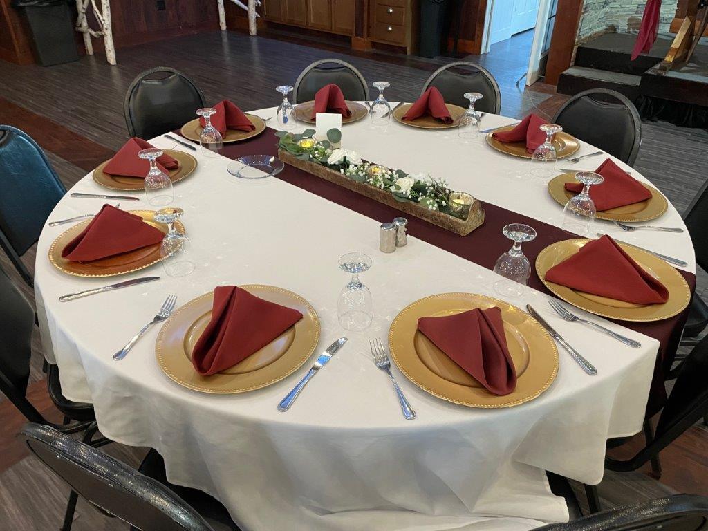 A round table with red napkins and gold plates.