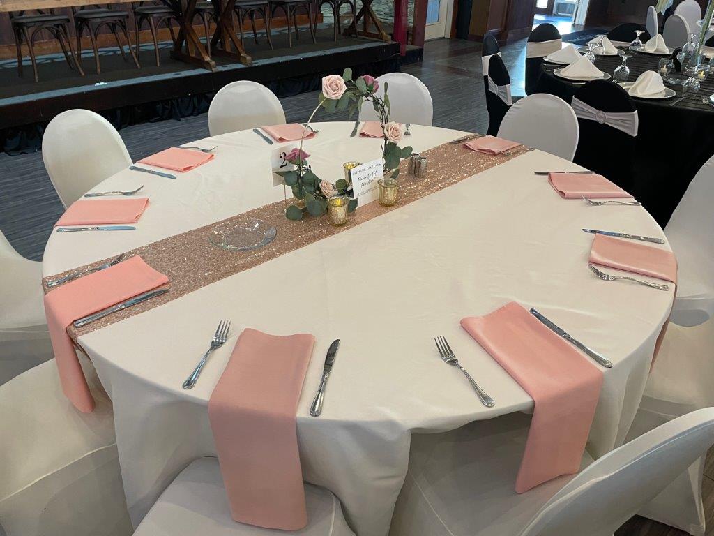 A table set with pink napkins and silverware.
