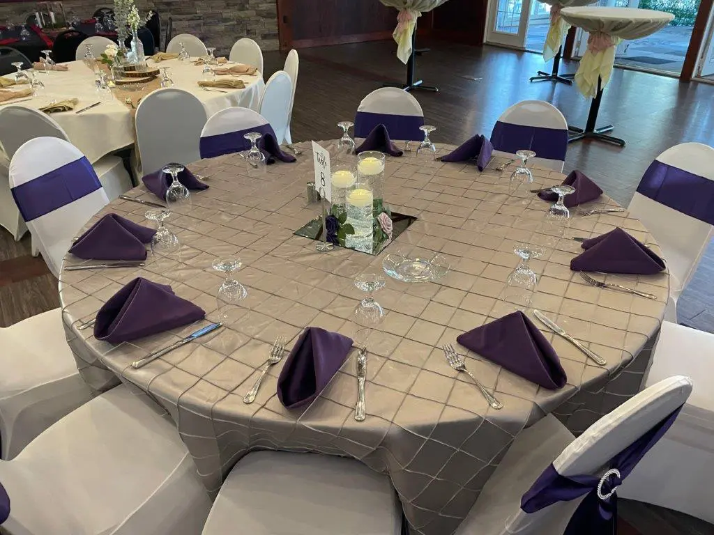 A table with purple napkins and white chairs