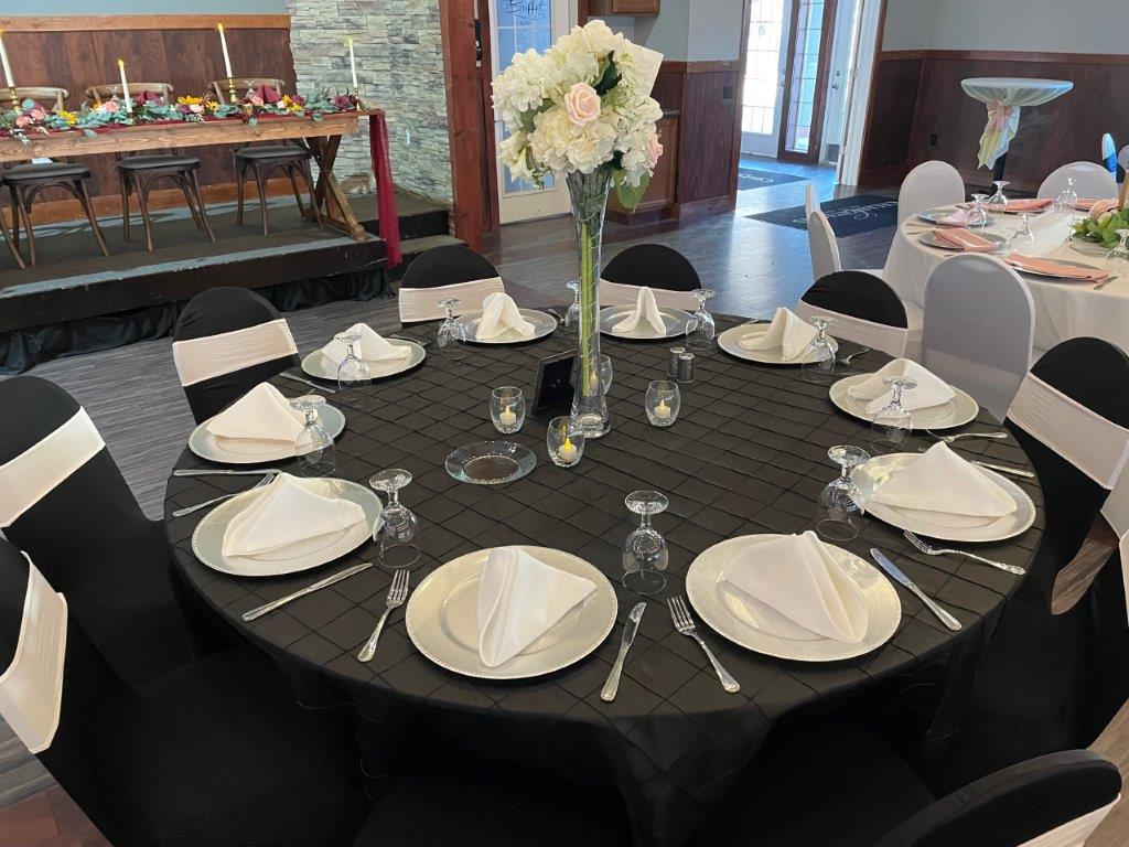 A table set with plates and silverware in front of a vase.