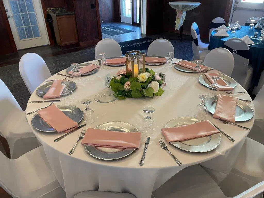 A table set with plates and silverware, napkins, and candles.