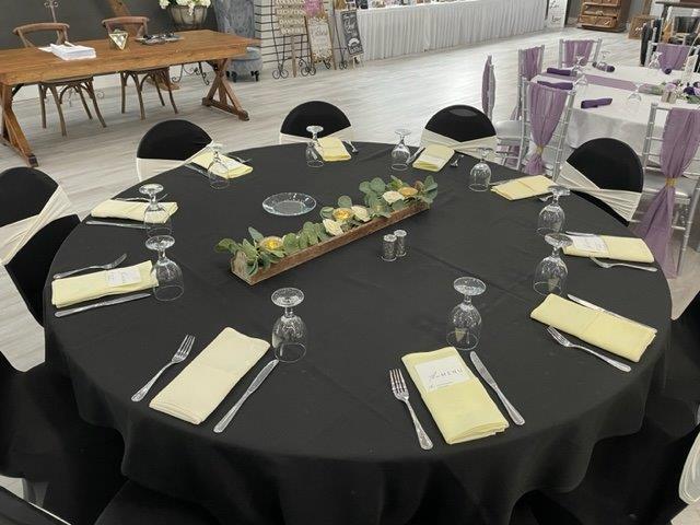 A table set with black linen and place settings.