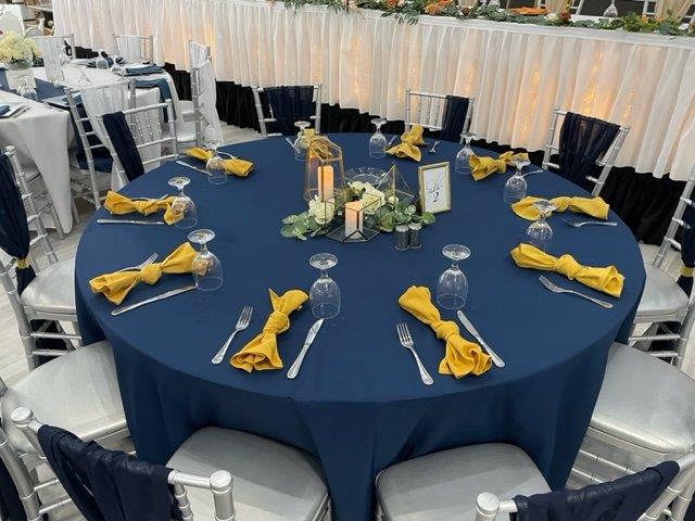 A table set with blue linens and yellow napkins.