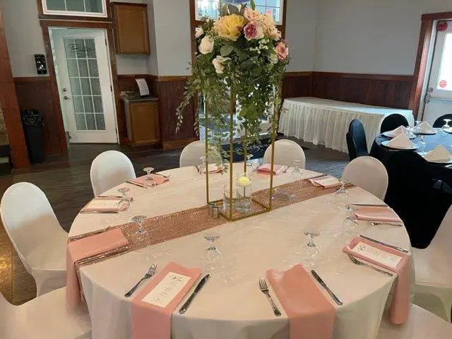 A table set up with pink napkins and white tablecloth.