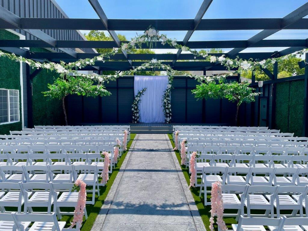 A wedding ceremony with white chairs and pink flowers.