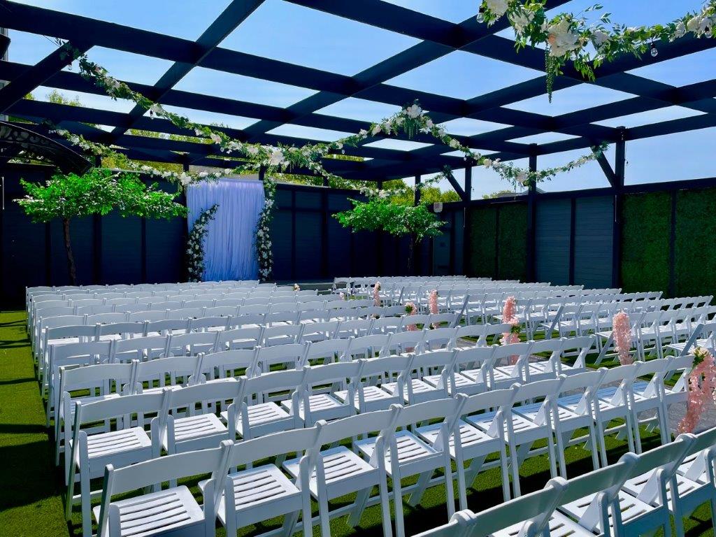 A large outdoor event with white folding chairs.