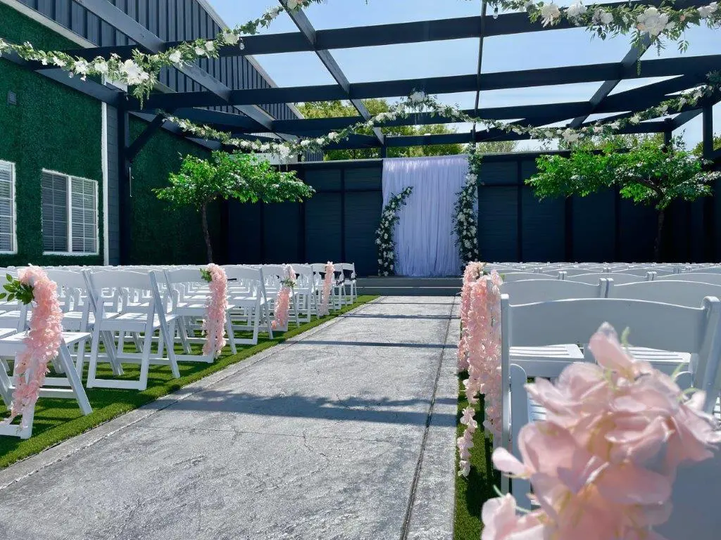 A wedding ceremony with pink flowers and white chairs.