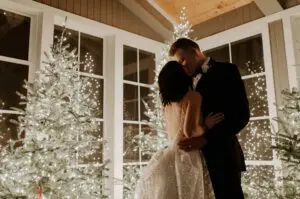 A man and woman kissing in front of christmas trees.