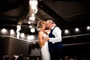 A bride and groom kissing in front of lights.
