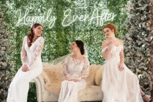 Three women in white gowns sitting on a couch.