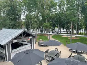 A patio with tables and umbrellas in the middle of a park.
