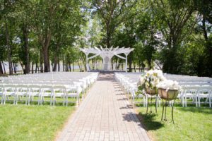 A wedding ceremony with white chairs and an arbor.